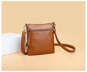 Close-up of caramel brown pebble leather texture and metal zipper on the shoulder bag