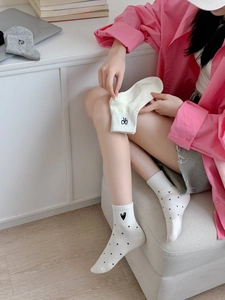 Detail of white cotton socks with black polka dots, hearts and bow patterns for women