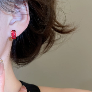 Macro side view of silver studs with red rectangular zircon stones worn by a model