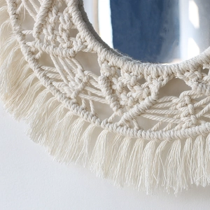 Detailed close-up of handmade macrame round wall mirror with cotton fringe and woven texture