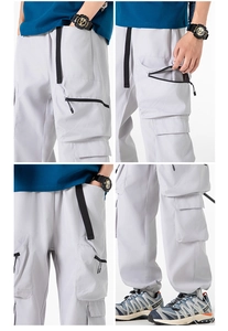 Dettaglio dei pantaloni cargo grigi che mostra il design multitasche e le cerniere tecniche