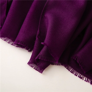 Detalle macro de una bufanda morada con textura de lino, tela suave y bordes de flecos