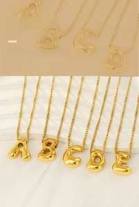 Detailed close-up of golden bubble initial necklaces with polished 3D alphabet charms