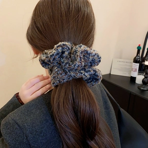 Chouchou en maille à carreaux bleu et marron porté en queue de cheval, décor d'hiver