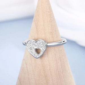 Detail of silver heart-shaped ring with micro-paved rhinestones on wooden stand