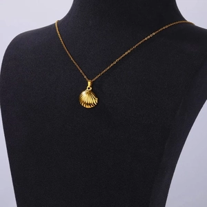 Detail of a golden scallop shell pendant necklace on a black textured bust stand