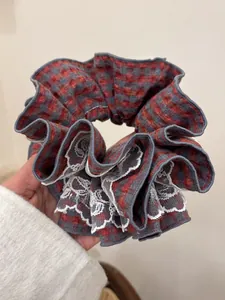 Detail showing red plaid oversized scrunchie with delicate white lace trim