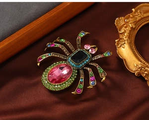Macro detail of vintage spider brooch with pink crystal and colorful rhinestone inlay