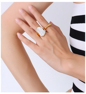 Dettaglio di anelli placcati oro 18K con madreperla bianca sulla mano di una modella