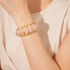 Detail of a vintage pink marble resin stretch bracelet with golden metal frame on a model
