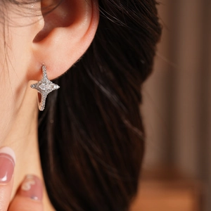 Close-up of starburst silver earrings with marquise-cut zircon on model's ear