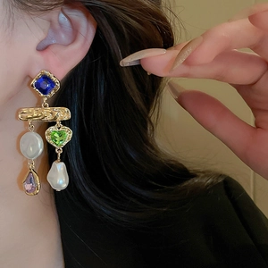Close-up of vintage baroque tassel earrings with faux pearls and colorful gemstones on a model