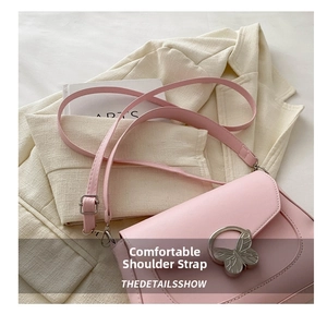 Detail of light pink shoulder bag with a decorative silver butterfly buckle and strap