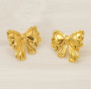 Macro detail of polished golden bow earrings featuring a smooth metallic reflective surface