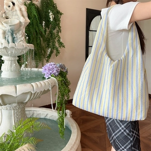 Detail of high-capacity striped canvas tote bag showing soft woven texture and shoulder fit