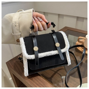 Detail of black matte bag with white plush trim, gold studs and leather handle
