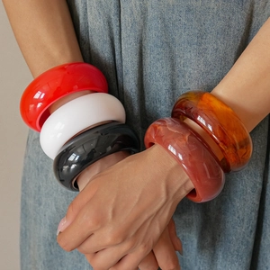 Close-up of chunky colorful resin bangles with marble texture on denim background