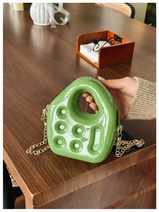 Detailed macro view of a green jelly PVC mini bag with embossed patterns and gold chain
