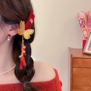 Detail of red velvet hair clip with golden butterfly and festive tassel bell decoration