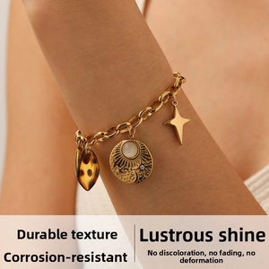 Detail of gold-plated chain bracelet with sun disk, star, and leopard print pendants