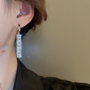 Macro shot of silver linear earrings with pavé cubic zirconia on a female model