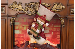 Detailed view of Christmas stocking with 3D snowman, birdhouse, and pinecones on a fireplace
