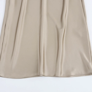 Détail de l'ourlet de la robe en satin champagne montrant la texture de soie et les coutures