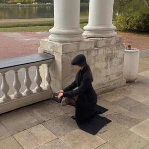 Manteau long élégant en laine noire avec revers et taille ajustée porté par un modèle