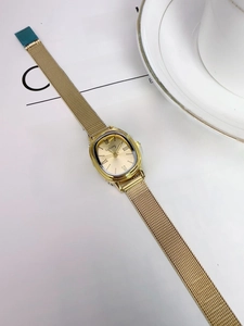 Detail of luxury gold quartz watch with mesh strap placed on a lifestyle magazine