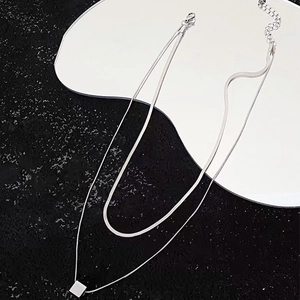 Detail of silver double-layer necklace with flat snake chain and square pendant