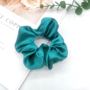 Detailed view of the peacock green satin oversized scrunchie with smooth silk texture