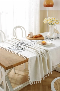Close-up of geometric embroidery and fringe detail on a white cotton linen tablecloth