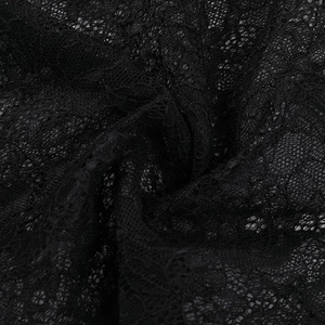 Gros plan sur le tissu en dentelle noire montrant la structure et les broderies