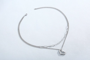Detail of silver layered necklace showing hollow heart pendant and mixed chain textures