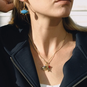 Exotic golden necklace with elephant pendant and blue evil eye earrings on female model