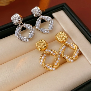 Close-up of gold and silver plated square pearl earrings in a beige velvet jewelry box