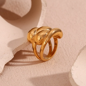 Detailed close-up of 18K gold plated stainless steel wavy dome ring on a beige surface