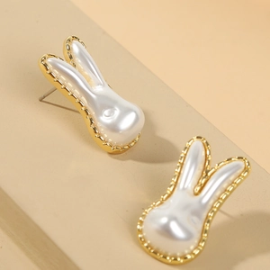 Detailed view of rabbit-shaped pearl earrings with elegant gold metal finish on warm base