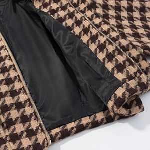 Detail of tweed jacket with houndstooth pattern, zipper closure and silky black lining