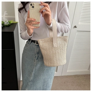 Detail of a straw bucket bag with synthetic leather handle shown in a mirror selfie