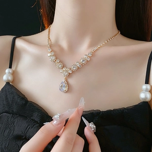 Détail d'un élégant collier doré avec un pendentif en zircone en forme de poire sur modèle