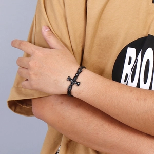 Macro shot of men's black cross pendant bracelet with fine chain on wrist