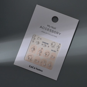 Close-up of MJ-052 nail art kit with silver metal shapes and white pearls on a card