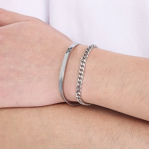 Detail of double layered silver titanium snake and cuban chain bracelets on wrist
