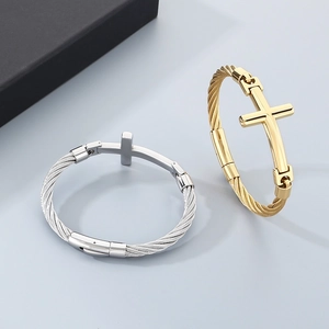 Retro rock style braided steel wire cross bracelet in gold and silver finish on gray background