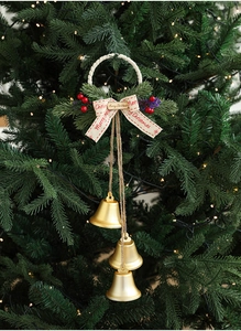Close-up of three golden Christmas bells with red berries on a festive tree branch
