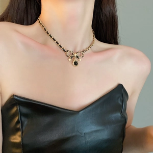 Detail of woven faux leather gold chain choker necklace with bow and round pendant