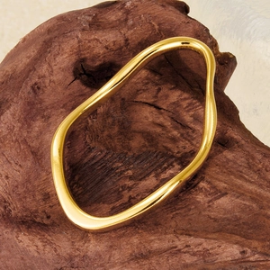 Detailed view of an irregular gold geometric pendant on a rustic wood pedestal
