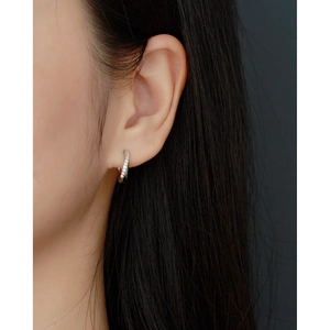 Macro side view of a model wearing a small silver S925 earring with clear zircon inlay
