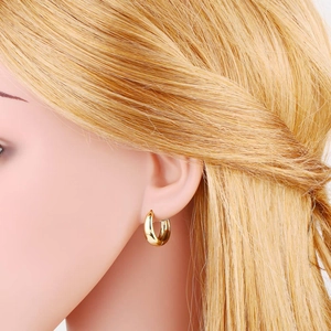 Close-up of chunky gold hoop earrings with a high-polished mirror finish on a model